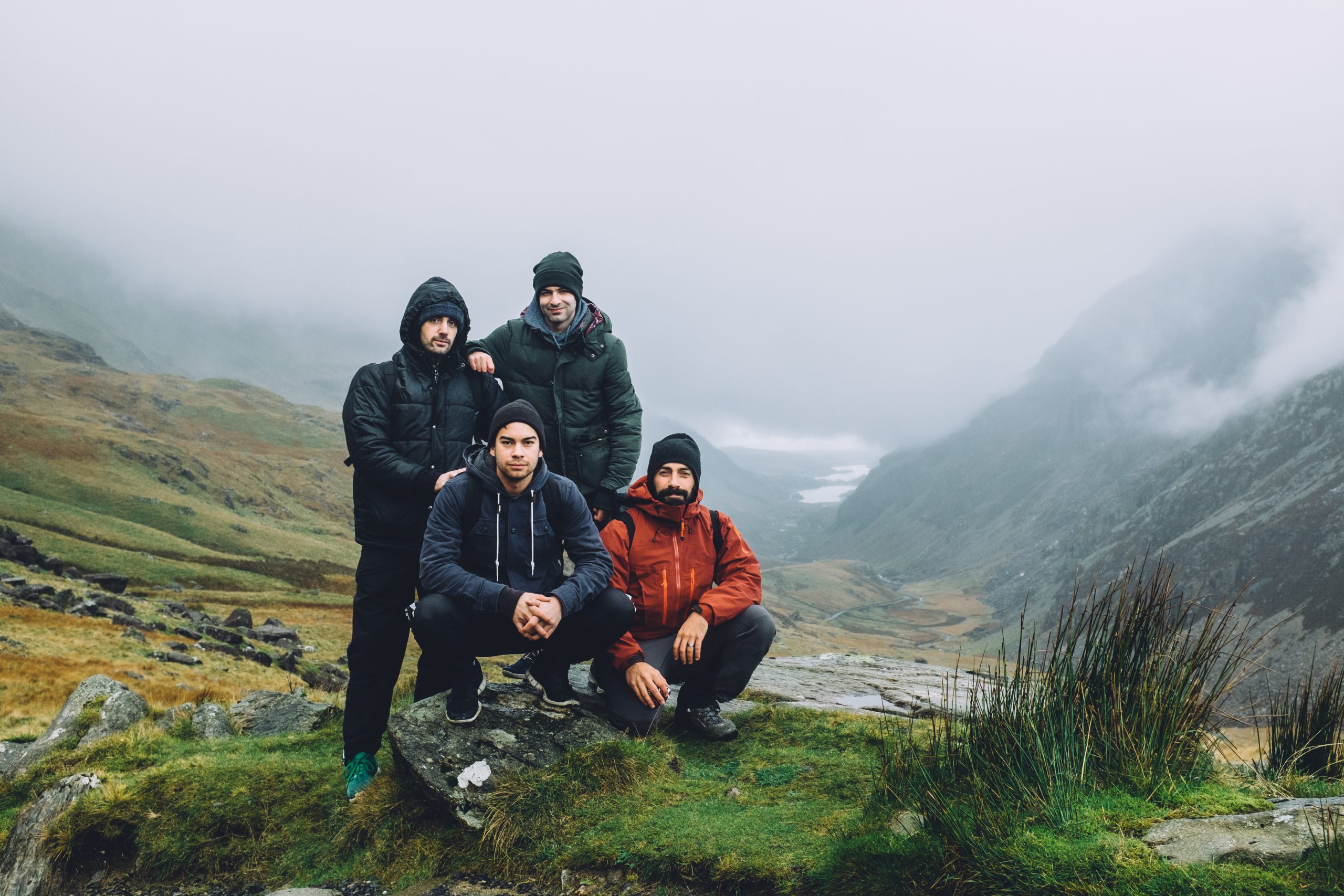 Four friends posing together on Mount Snowdon on a cloudy, wet, day.